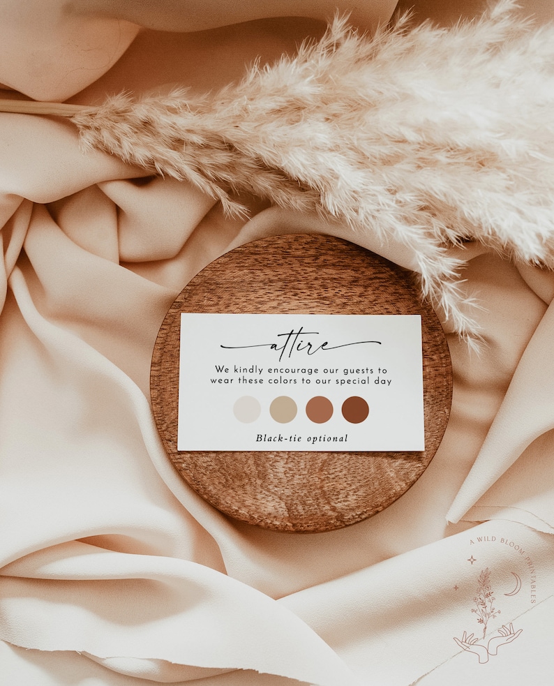 May include: A white card with the word "attire" written in cursive. The card has a message encouraging guests to wear colors in shades of beige, brown, and orange. The card also states "Black-tie optional". The card is sitting on a wooden coaster.