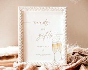 May include: White sign with a gold frame and the text "cards and gifts" with two champagne glasses and the text "Thank you" and "Haydin's Bridal Shower 09.23.24".