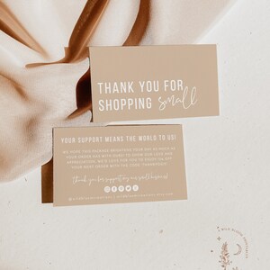May include: Thank you for shopping small card with a beige background and white text. The card includes a message thanking customers for their support and offering a discount code for their next purchase. The card also includes social media icons and a website address.