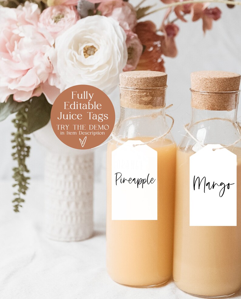 May include: Two glass bottles with cork tops filled with orange juice.  The bottles have white tags with black handwritten text that reads "Pineapple" and "Mango".  The bottles are sitting on a white surface with a white vase and pink flowers in the background.  The image includes a brown circle with the text "Fully Editable Juice Tags" and "Try the Demo in Item Description".