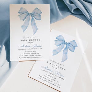Może przedstawiać: Dwa zaproszenia na baby shower z akwarelowym wzorem niebieskiej kokardy. Zaproszenia zawierają tekst "BABY SHOWER w hołdzie dla Madison Johnson" oraz szczeg&oacute;ły wydarzenia. Zaproszenia są na białym tle.
