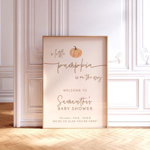 May include: A 24x36 inch poster featuring a watercolor pumpkin illustration and text that reads: a little pumpkin is on the way, WELCOME TO Samantha's BABY SHOWER, October 18th, 20XX, WE'RE SO GLAD YOU'RE HERE! The sign has a light beige background.