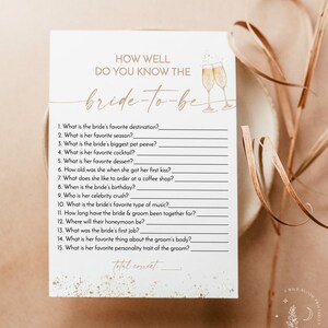May include: A printable bridal shower game with a gold glitter background and the text "How well do you know the bride-to-be?"  The game includes 15 questions about the bride and her fiance.