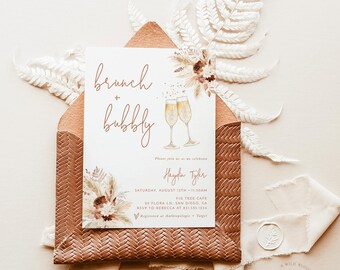 Puede incluir: Una tarjeta blanca con texto marrón anunciando una celebración de brunch y burbujas para Haydia Tyler. El evento se llevará a cabo el sábado 12 de agosto a las 11:30 AM en Fig Tree Cafe, 29 Flora Ln., San Diego, CA. RSVP a Rebecca al 831-555-1234. La tarjeta está decorada con una ilustración de acuarela de copas de champán y flores secas.