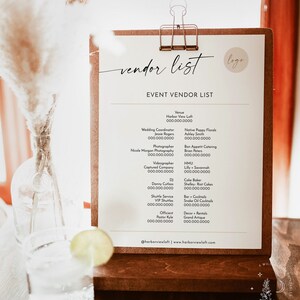Pu&ograve; includere: Una clipboard bianca con una cornice in legno marrone e una clip dorata. La clipboard contiene un elenco di fornitori di matrimoni in bianco e nero. L'elenco include i nomi e le informazioni di contatto del luogo, del coordinatore di matrimoni, del fotografo, del videomaker, del DJ, del servizio navetta, dell'ufficiante, del fiorista, del catering, dell'artista di trucco e parrucco, del pasticcere, del bar e del noleggio di decorazioni.