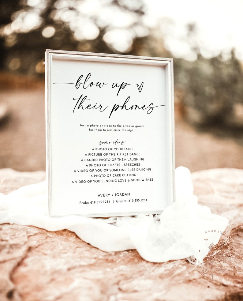 May include: A white sign with black text that reads "blow up their phones" and includes instructions for guests to text photos or videos to the bride and groom. The sign also includes a list of ideas for photos and videos, such as a photo of the table, a picture of their first dance, and a video of cake cutting. The sign also includes the bride and groom's names and phone numbers.