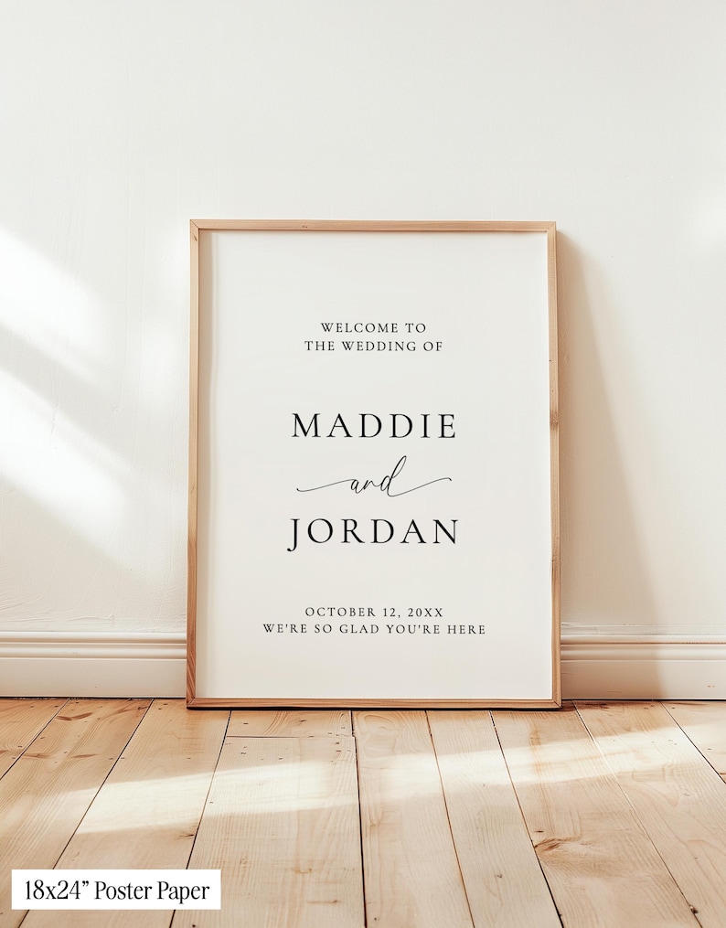 May include: A vertical wedding welcome sign in a light wood frame featuring black text on a white background that reads: WELCOME TO THE WEDDING OF MADDIE and JORDAN OCTOBER 12, 20XX WE'RE SO GLAD YOU'RE HERE. The sign measures 18x24 inches.