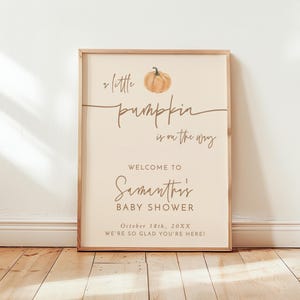 May include: A rectangular poster in a wooden frame featuring a watercolor pumpkin illustration and the text: A little pumpkin is on the way, Welcome to Samantha's Baby Shower, October 18th, 20XX, We're so glad you're here. The poster measures 18x24 inches.
