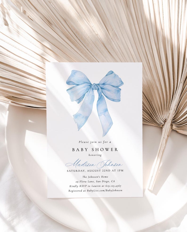 Może przedstawiać: Zaproszenie na baby shower z akwarelową niebieską kokardą. Zaproszenie zawiera tekst "Please join us for a BABY SHOWER honoring Madison Johnson" oraz szczeg&oacute;ły wydarzenia. Projekt jest na białym tle.