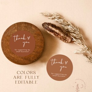 May include: Two round thank you stickers with a brown background and white text. The text on the stickers reads "thank you" with a heart symbol and "for supporting my small business!"  The stickers are on a wooden surface. The text "COLORS ARE FULLY EDITABLE" is below the stickers.