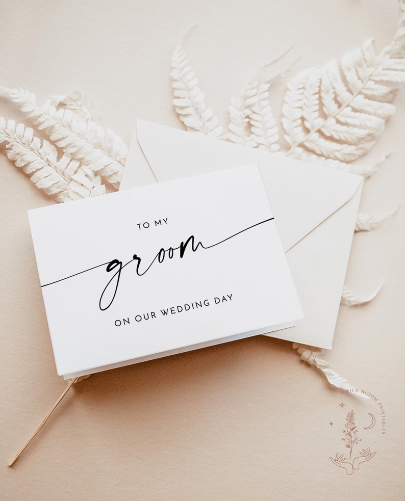 Op de afbeelding: Een witte kaart met zwarte tekst die "To my groom on our wedding day" zegt.
