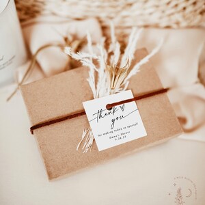 May include: A small brown gift box with a white tag tied with a brown ribbon. The tag says "Thank you for making today so special! Emma's Shower 9.24.25".