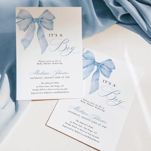 May include: Blue watercolor bow with the text "It's a Boy" on a white card with a brown border. The card is a baby shower invitation for Madison Johnson. The invitation includes the date, time, location, and RSVP information.