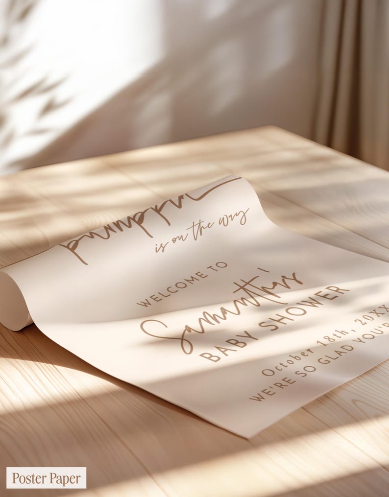 May include: A rolled poster paper sign with a light beige background and brown text that reads: pumpkin is on the way, WELCOME TO Samantha's BABY SHOWER, October 18th, 20XX, WE'RE SO GLAD YOU'RE HERE.