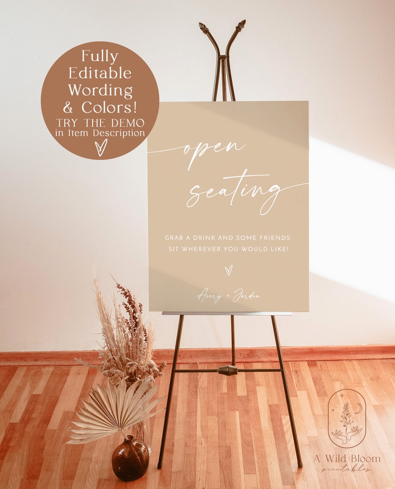 May include: A printable sign with the text "open seating" in white script font on a beige background. The sign also includes the text "Grab a drink and some friends. Sit wherever you would like!" and the names "Aury + Jorden" in white script font. The sign is on a black easel.