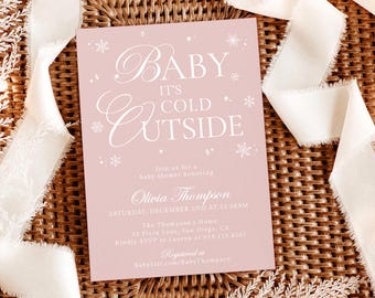 May include: A pink baby shower invitation with the text "Baby It's Cold Outside" in elegant script. The invitation includes details for Olivia Thompson's baby shower, set against a woven background with white ribbons and decorative elements.