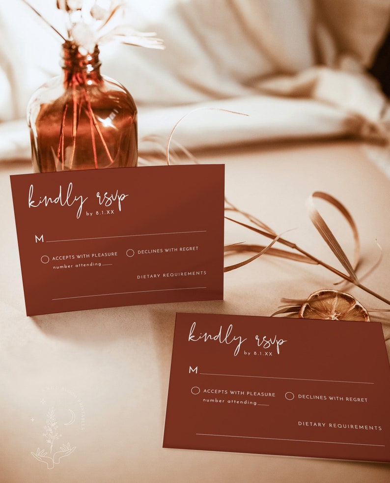 May include: Two brown RSVP cards with white text. The text on the cards reads "kindly rsvp by 8.1.XX". Each card has a section for the guest to indicate whether they will accept or decline the invitation, and a space for the guest to write the number of people attending. There is also a space for the guest to write any dietary requirements.