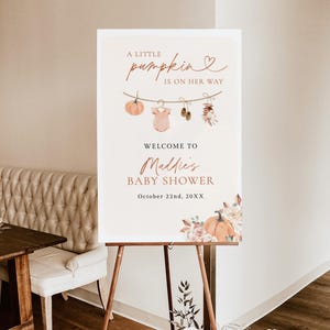 May include: A 24x36 inch foam board sign for a baby shower with the text A LITTLE pumpkin IS ON HER WAY, WELCOME TO Maddie's BABY SHOWER, and October 22nd, 20XX. The design features a clothesline with a pumpkin, onesie, shoes, and flowers.