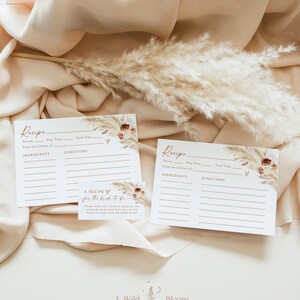 Pu&ograve; includere: Due schede di ricette stampabili con un tema boho. Le schede hanno uno sfondo marrone chiaro con un design floreale e un carattere scritto a mano. Il testo sulle schede recita "Ricetta" e include spazi per il nome della ricetta, le porzioni, il tempo di preparazione, il tempo totale, gli ingredienti e le istruzioni. Una scheda pi&ugrave; piccola con un design simile recita "Una ricetta per la sposa".