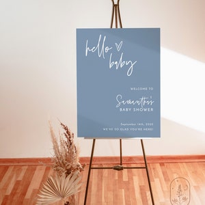 Może przedstawiać: Niebieski napis powitalny z białym tekstem, kt&oacute;ry brzmi "hello baby" i "Witamy na Baby Shower Samanthi" z datą "14 września 2025" i tekstem "Cieszymy się, że jesteś!" Napis stoi na czarnym sztalugach.