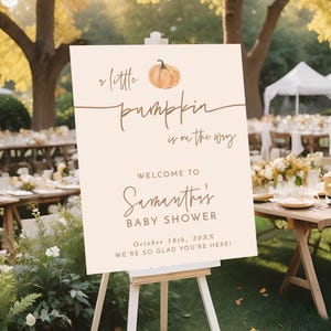 May include: A rectangular 18x24 inch foam board sign on a white easel. The sign is cream-colored with a watercolor pumpkin illustration and brown text reading: A little pumpkin is on the way, Welcome to Samantha's Baby Shower, October 18th, 20XX, WE'RE SO GLAD YOU'RE HERE!