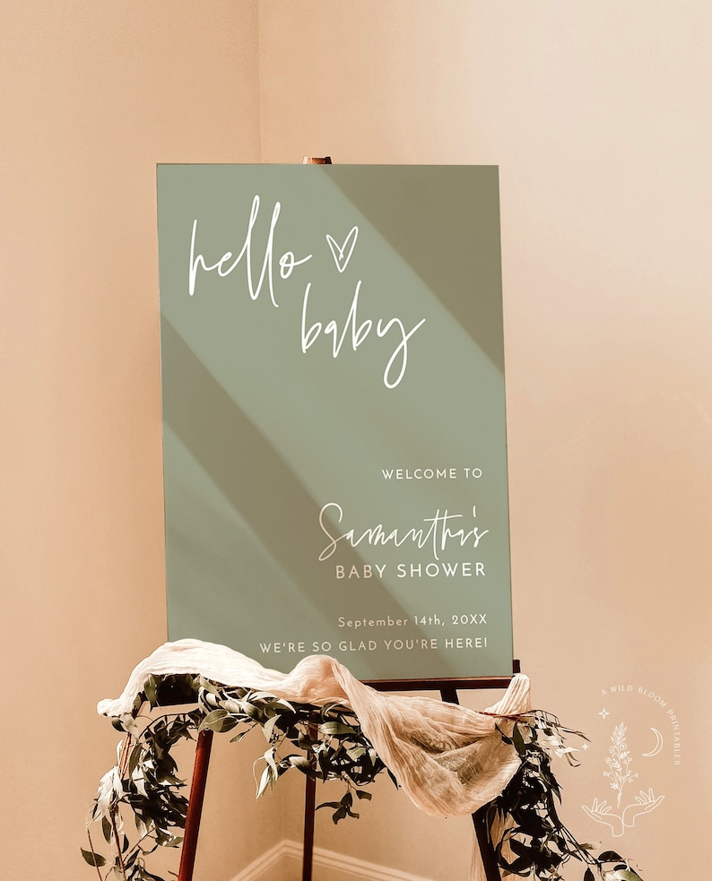 May include: A sage green welcome sign with white calligraphy that reads "hello baby" and "Samantha's Baby Shower". The sign also includes the date "September 14th, 20XX" and the phrase "We're so glad you're here!"