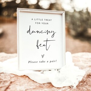 Op de afbeelding: Een wit bord met zwarte tekst dat "A little treat for your dancing feet. Please take a pair!" zegt. Het bord staat op een rots met een witte doek eroverheen.