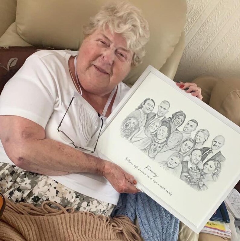 Pu&ograve; includere: Una donna tiene in mano un disegno a matita in bianco e nero incorniciato di un ritratto di famiglia. Il disegno include pi&ugrave; persone, un cane e il testo "Family Where life begins and love never ends".