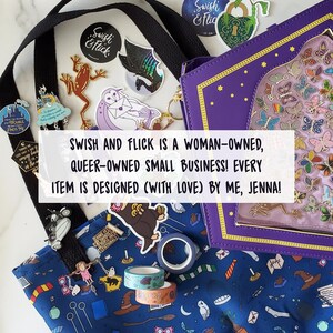K&ouml;nnte beinhalten: Eine blaue Tragetasche mit einem fantasievollen Muster aus Eulen, Sternen und anderen magischen Bildern. Die Tasche ist mit verschiedenen Aufklebern verziert, darunter eine lila Eule mit einem Brief, ein schwarzer Drache und ein Frosch. Der Text "Swish and Flick" ist auf einem Aufkleber sichtbar. Die Tasche wird von einer lila, buchf&ouml;rmigen Clutch mit einem durchsichtigen Fenster begleitet, das bunte Schmetterlinge enth&uuml;llt. Der Text "SWISH AND FLICK IS A WOMAN-OWNED, QUEER-OWNED SMALL BUSINESS! EVERY ITEM IS DESIGNED (WITH LOVE) BY ME, JENNA!" ist auf einem wei&szlig;en Banner sichtbar.