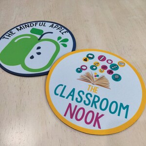 May include: Two round mouse pads. One features a green apple graphic with the text "THE MINDFUL APPLE" in a circular design. The other has the text "THE CLASSROOM NOOK" with various icons and an open book graphic.