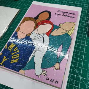 May include: A completed jigsaw puzzle featuring a group of four women with different skin tones and hair colors. The puzzle has a pink background with the text "El coraz&oacute;n guarda lo que el alma toca" and the date "14.02.21".