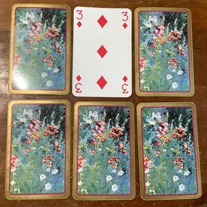 May include: A set of six playing cards featuring a floral design with red, white and green flowers. The cards are numbered 3 of diamonds and 2 of diamonds.