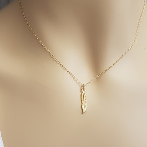 Pode incluir: Um colar de corrente de ouro com um delicado pingente de pena.