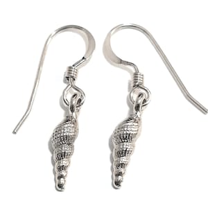 May include: A pair of silver earrings featuring a detailed seashell design. The earrings have a simple hook closure.