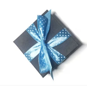 May include: A gray gift box with a blue ribbon and white polka dots. The ribbon is tied in a bow on top of the box.