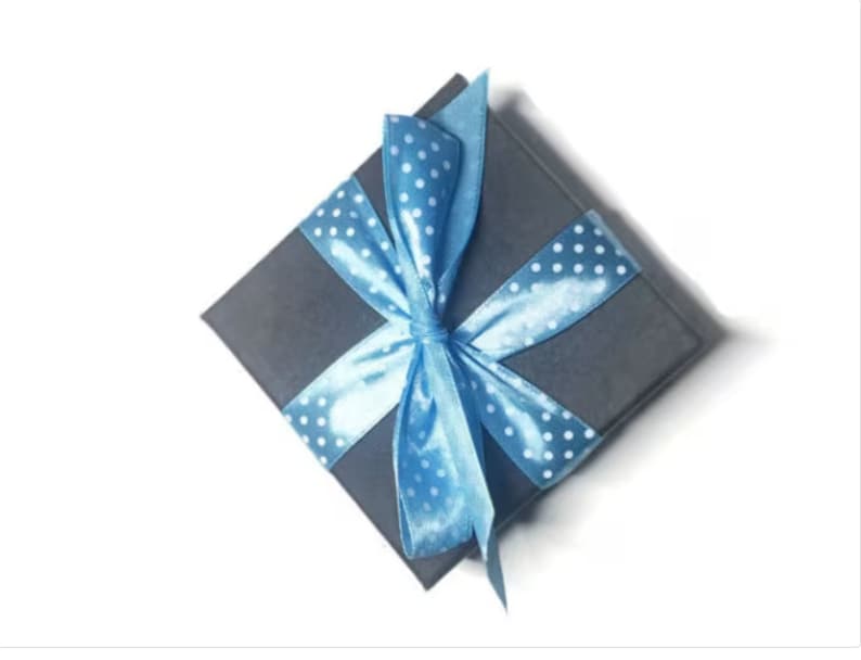 May include: A gray gift box with a blue ribbon and white polka dots. The ribbon is tied in a bow on top of the box.