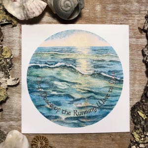Pode incluir: Uma impressão quadrada com uma pintura em aquarela de ondas oceânicas em tons de azul e verde, com um sol dourado se pondo no horizonte. O texto "Deep Peace of the Running Wave to You" está escrito em um círculo ao redor da imagem.