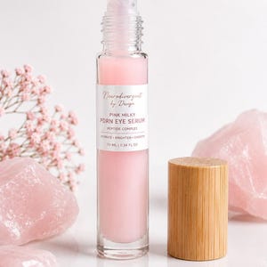 Peut inclure: Un flacon &agrave; bille en verre transparent contenant un s&eacute;rum pour les yeux rose laiteux PDRN avec un complexe peptidique. L'&eacute;tiquette indique Neurodivergent by Design, Pink Milky PDRN Eye Serum, Peptide Complex, Hydrate, Brighten, Smooth, 10 ml.