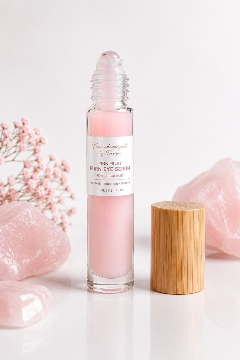 Peut inclure: Un flacon &agrave; bille en verre transparent contenant un s&eacute;rum pour les yeux rose laiteux PDRN avec un complexe peptidique. L'&eacute;tiquette indique Neurodivergent by Design, Pink Milky PDRN Eye Serum, Peptide Complex, Hydrate, Brighten, Smooth, 10 ml.