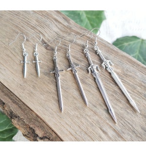 May include: Five pairs of silver sword earrings. The earrings are all different styles, with some featuring intricate details.