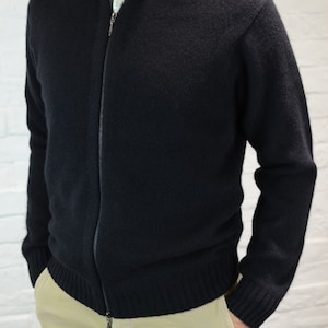 Könnte beinhalten: Ein schwarzer Reißverschluss-Pullover mit Stehkragen und Rippenbündchen. Der Pullover ist aus einem weichen, bequemen Material gefertigt.