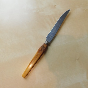 May include: A silver butter knife with a brown wooden handle. The knife has the text "Solingen" on the blade.