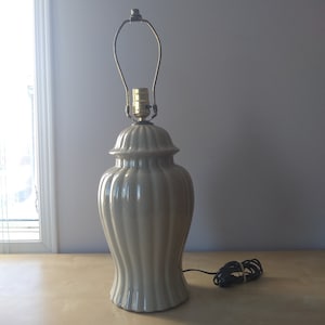 Peut inclure: Une lampe de table en céramique grise avec une base cannelée et un abat-jour simple en métal doré.