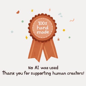 May include: A brown ribbon with a round, orange badge that says "100% hand made". The badge is decorated with small white dots. The ribbon is against a white background with small, colorful dots.