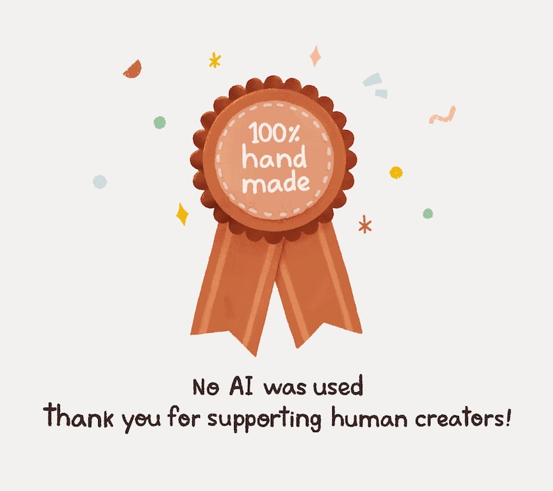 May include: A brown ribbon with a round, orange badge that says "100% hand made". The badge is decorated with small white dots. The ribbon is against a white background with small, colorful dots.
