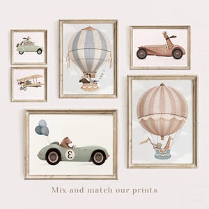 May include: Set of five framed prints featuring whimsical illustrations of hot air balloons, airplanes, and cars. The prints are in a light brown frame with a white mat. The illustrations feature animals like giraffes, bears, and elephants.