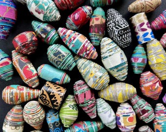 May include: A collection of colorful, handmade paper beads in various sizes and patterns. The beads feature a mix of vibrant colors, including red, green, blue, and yellow, with intricate designs. These beads are perfect for jewelry making.