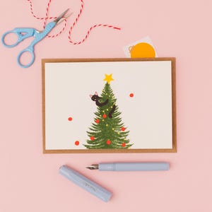 Naughty black cat up the Christmas tree- Christmas greetings card