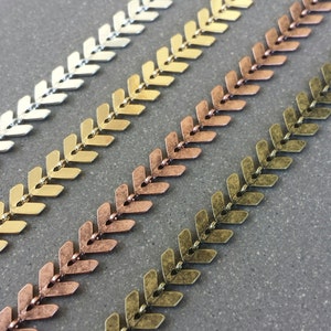 May include: Four strands of metal chain with a chevron pattern. The chains are in silver, gold, copper, and bronze.