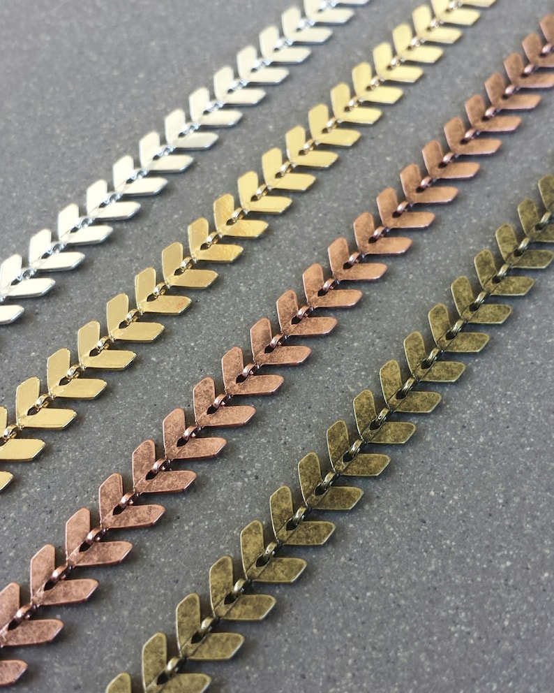 May include: Four strands of metal chain with a chevron pattern. The chains are in silver, gold, copper, and bronze.